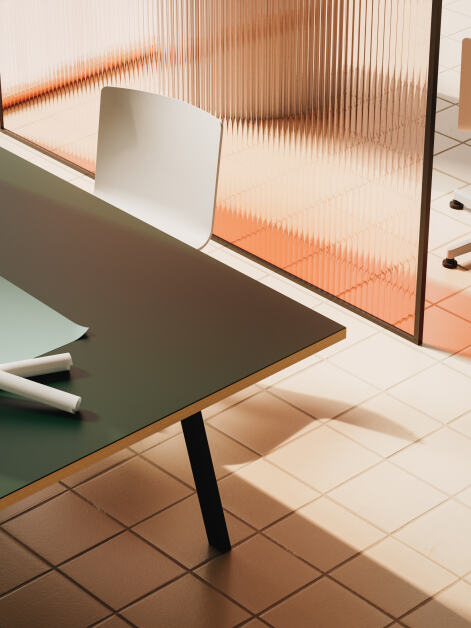 A few DIN tables designed by Michel Charlot, featuring Conifer linoleum tabletops with wooden edges and sturdy black metal legs. Each table hosts two facing workstations, each equipped with essential office items, creating a functional workspace.