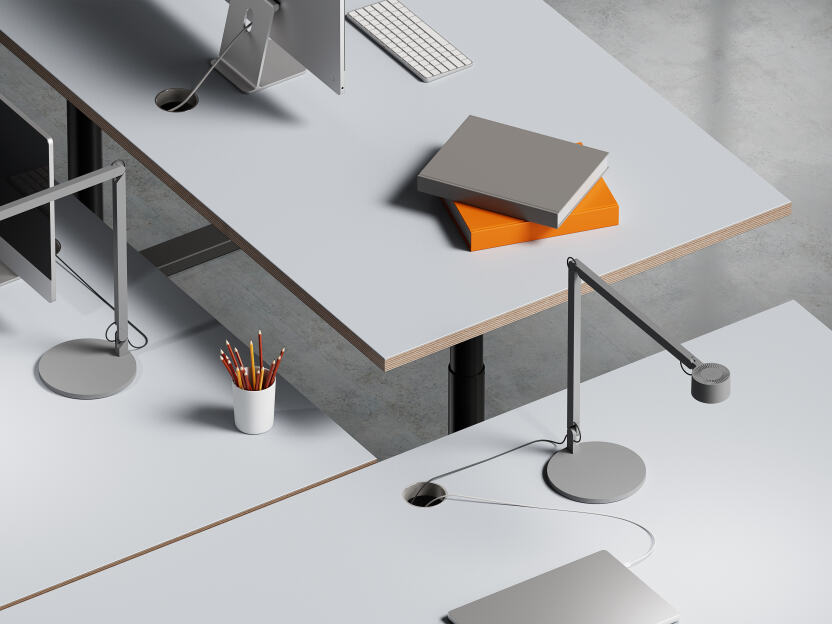 A group of three ATS tables by Faust in an office environment, including two at standard height and one elevated for a standing work position. The tables have black metal stands with a round profile and Vapour linoleum tabletops with plywood edges. They i