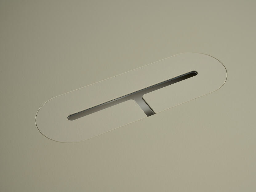 An anodised aluminum oval cable lid by Daniel Lorch, covered with Vapoor linoleum on one side. It sits on its tabletop cut-out hole, effectively organising cables, and protecting them from abrasion.