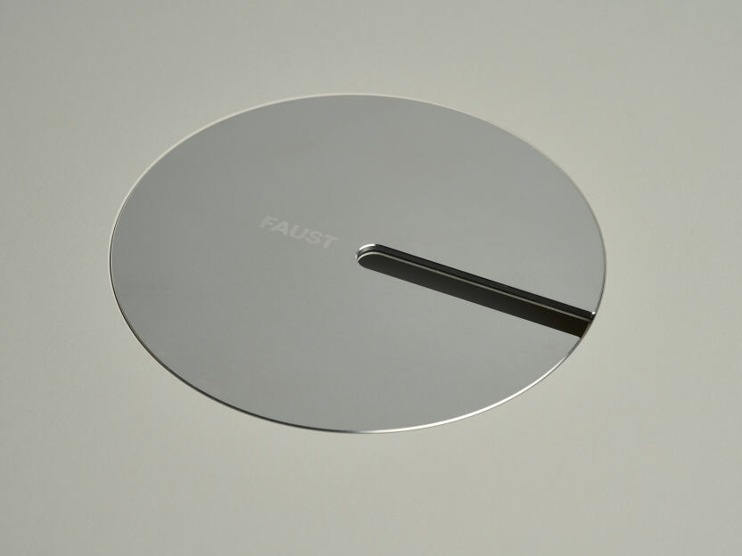 An anodised aluminum oval cable lid by Daniel Lorch. It sits on its tabletop cut-out hole, effectively organising cables, and protecting them from abrasion.