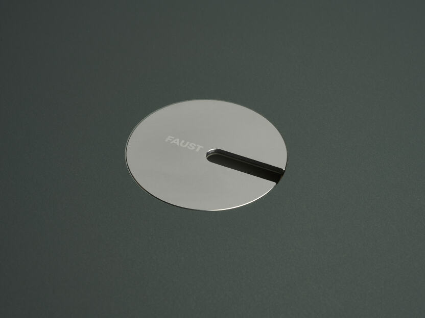 An anodised aluminum round cable lid by Daniel Lorch. It sits on its tabletop cut-out hole, effectively organising cables, and protecting them from abrasion.