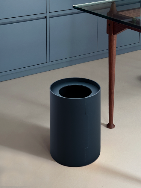 One TIDY Paper Bin by Keiji Takeuchi in Smokey Blue linoleum next to a table with wooden legs in an office set-up