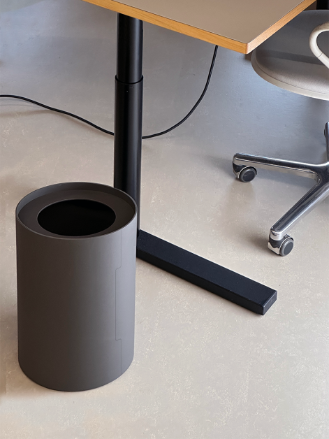 Tidy Paper Bin by Keiji Takeuchi in Iron Grey linoleum placed next to a height-adjustable ATS table in an office setup