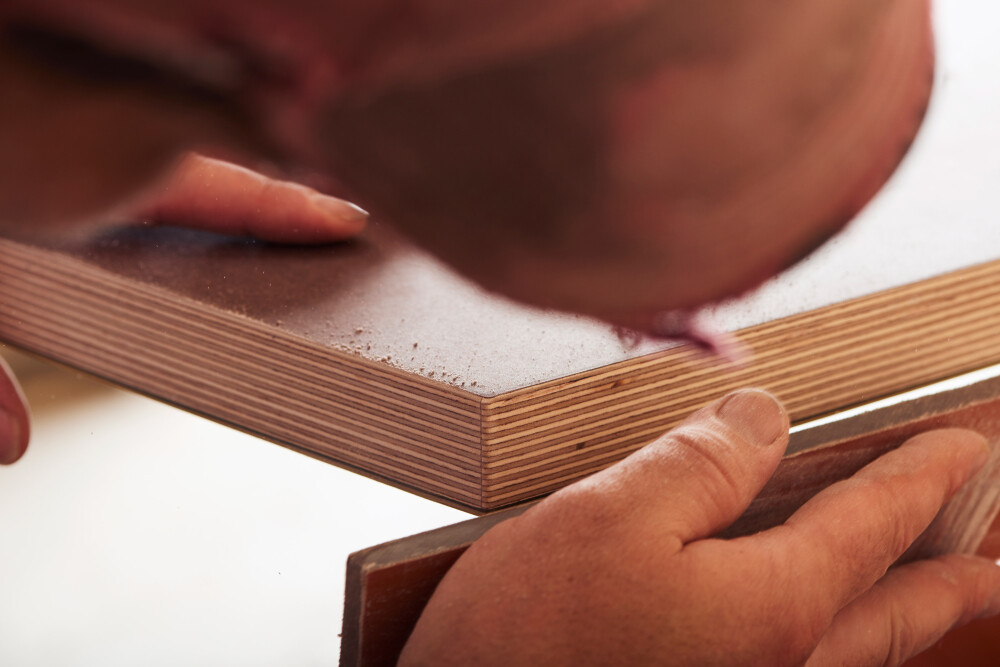 Faust Linoleum expert carpenter hand sanding tabletop wooden edges during production