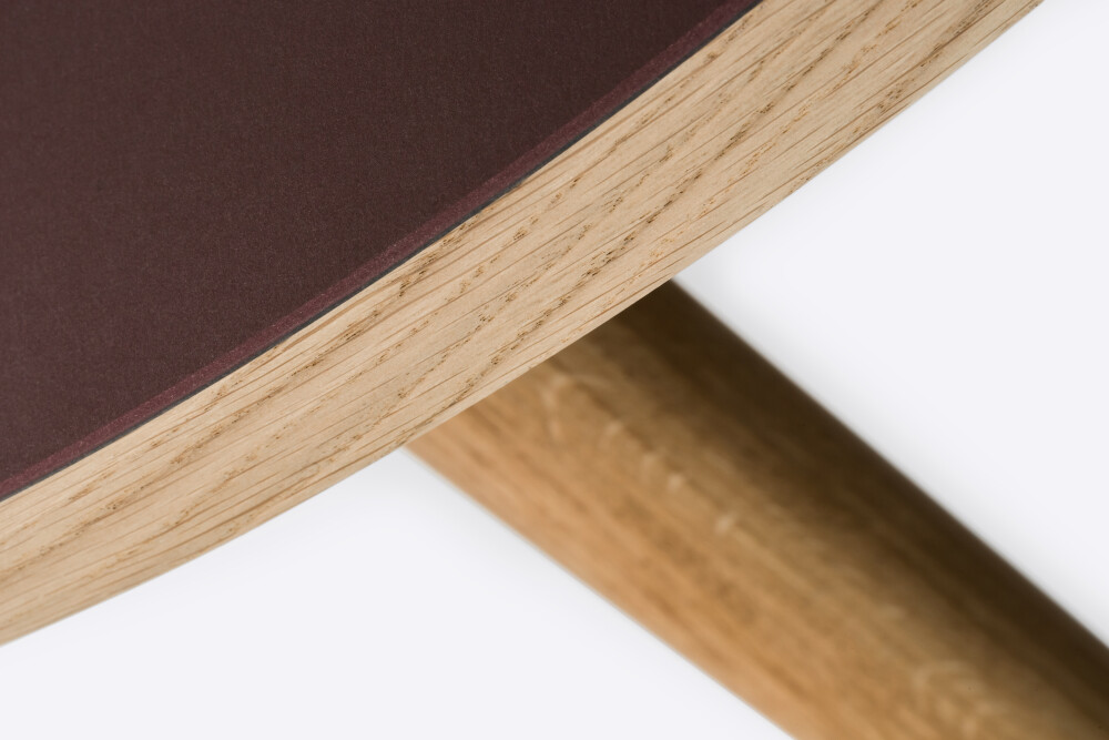 Detail of a round wooden tabletop lined in Burgundy linoleum and mounted on MT2 oak legs by Murken Hansen for FAUST Linoleum