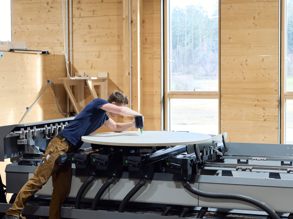 Manuelle CNC-Bearbeitung einer runden Linoleum-Tischplatte bei Faust – präzises Fräsen im Tageslicht durch geschultes Fachpersonal.