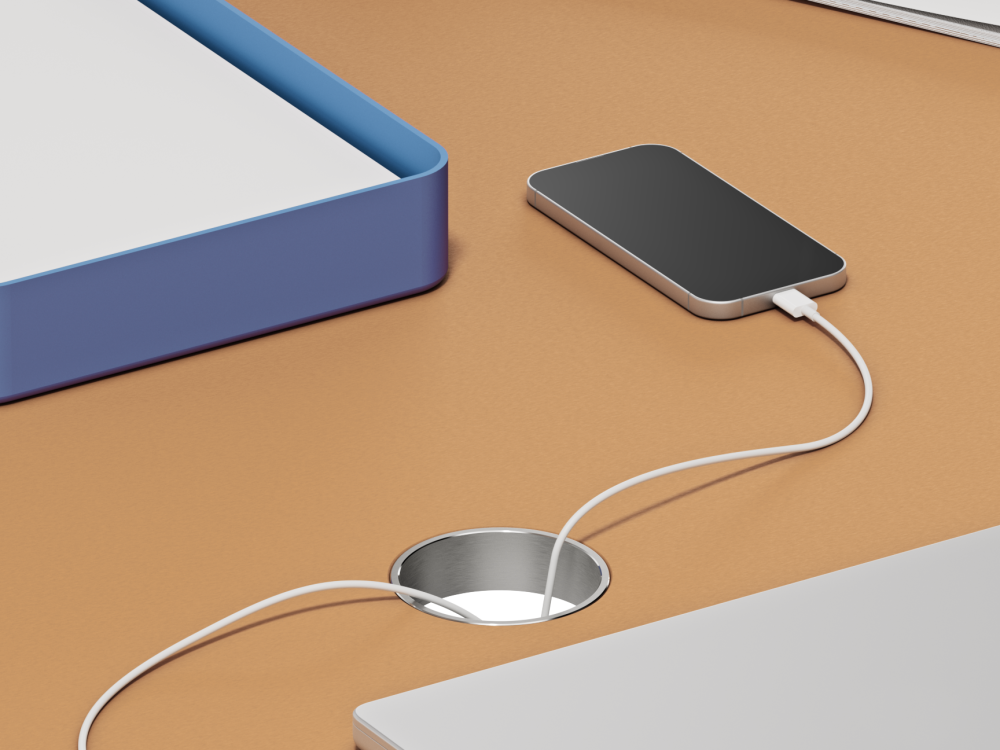 Aluminum cable outlet, round and embedded in linoleum tabletop from Faust – with visible charging cables for laptop and smartphone.
