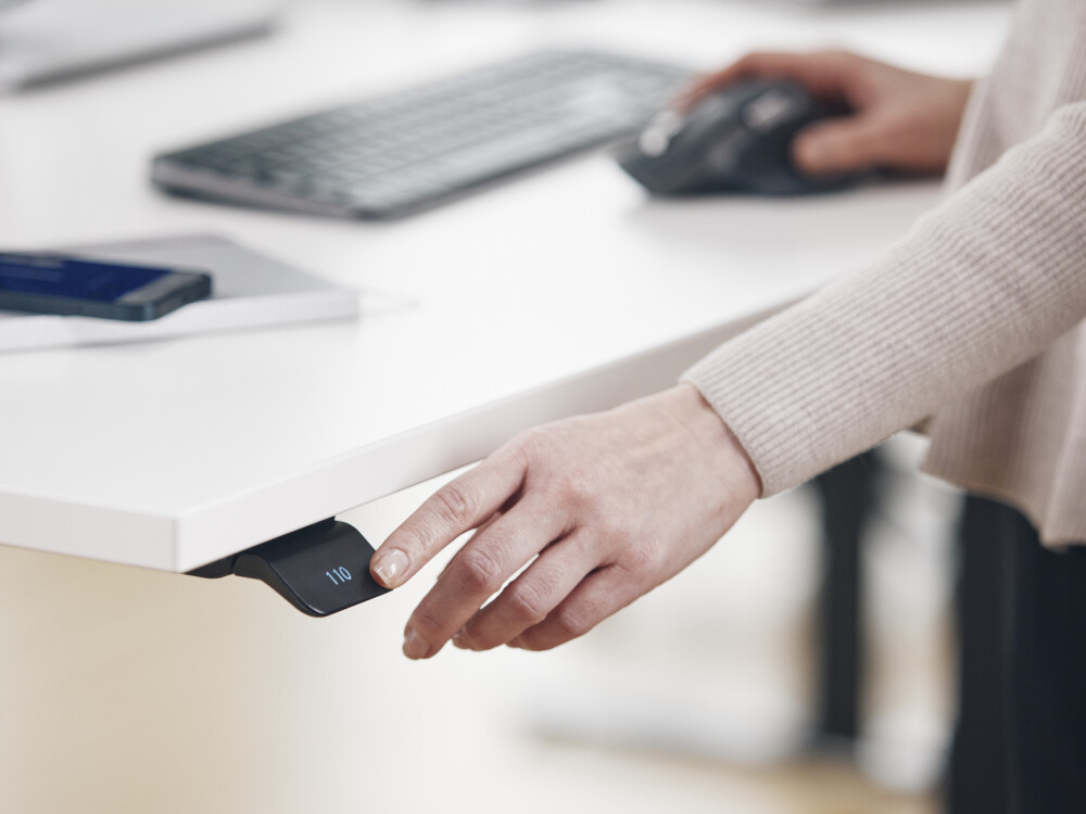 White ATS desk with integrated standard control display for height adjustment, shown in a modern office environment.