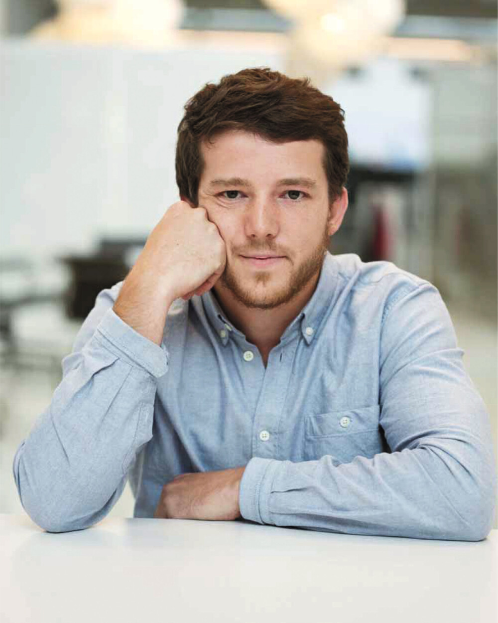 Michel Charlot, Swiss industrial designer - in a portrait for Faust, sitting at a table, wearing a light-colored shirt and looking directly at the camera.