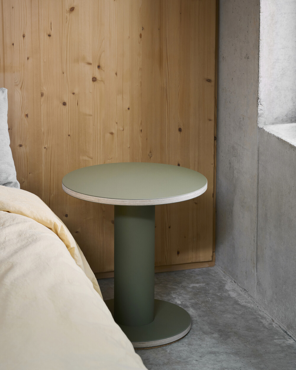 Faust OFF-CUT side table in olive with round linoleum top, used as a bedside table in the bedroom.