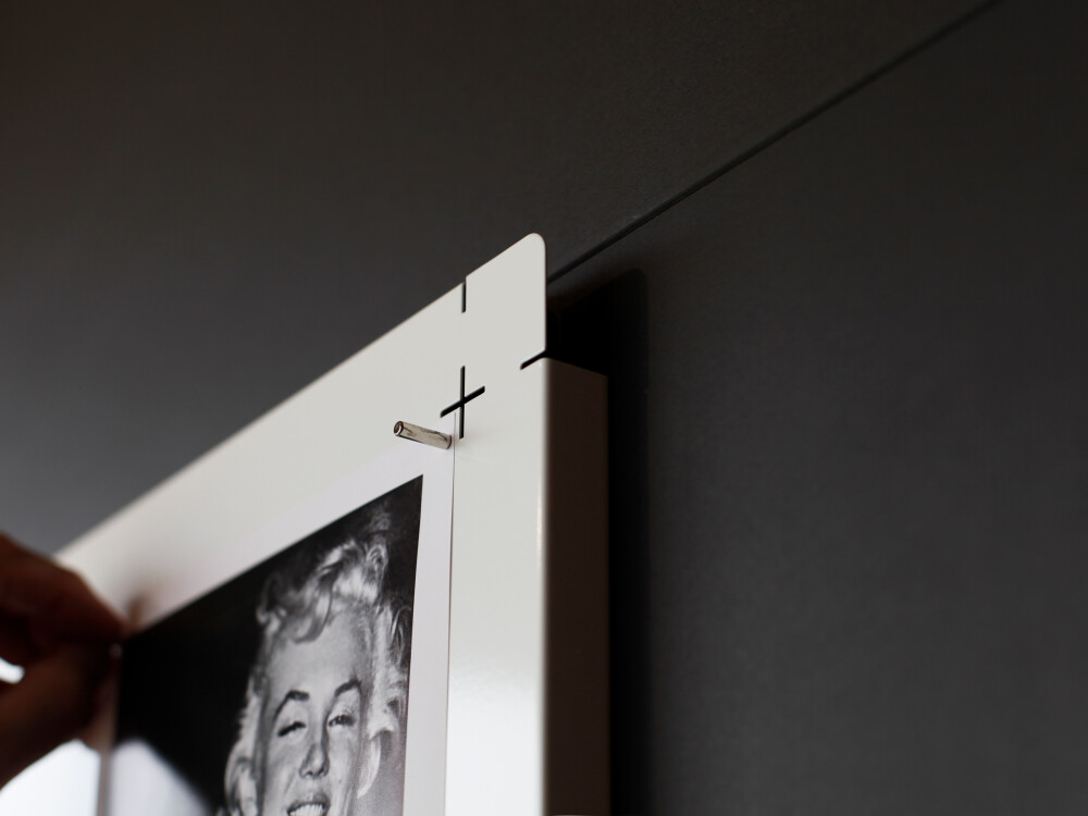 Detailed view of a corner of the PIN magnetic board made of folded steel, to which a photograph is attached with a magnet.