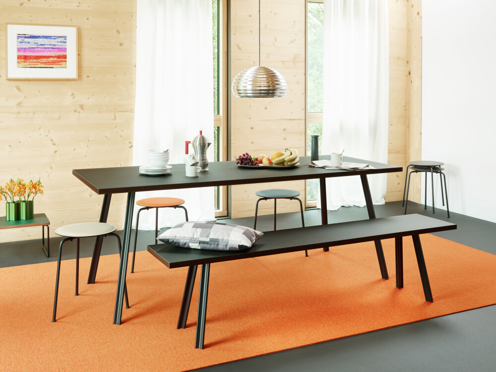 Dining room scene with BEAM bench and table in black linoleum, combined with colourful RAVIOLI stools.