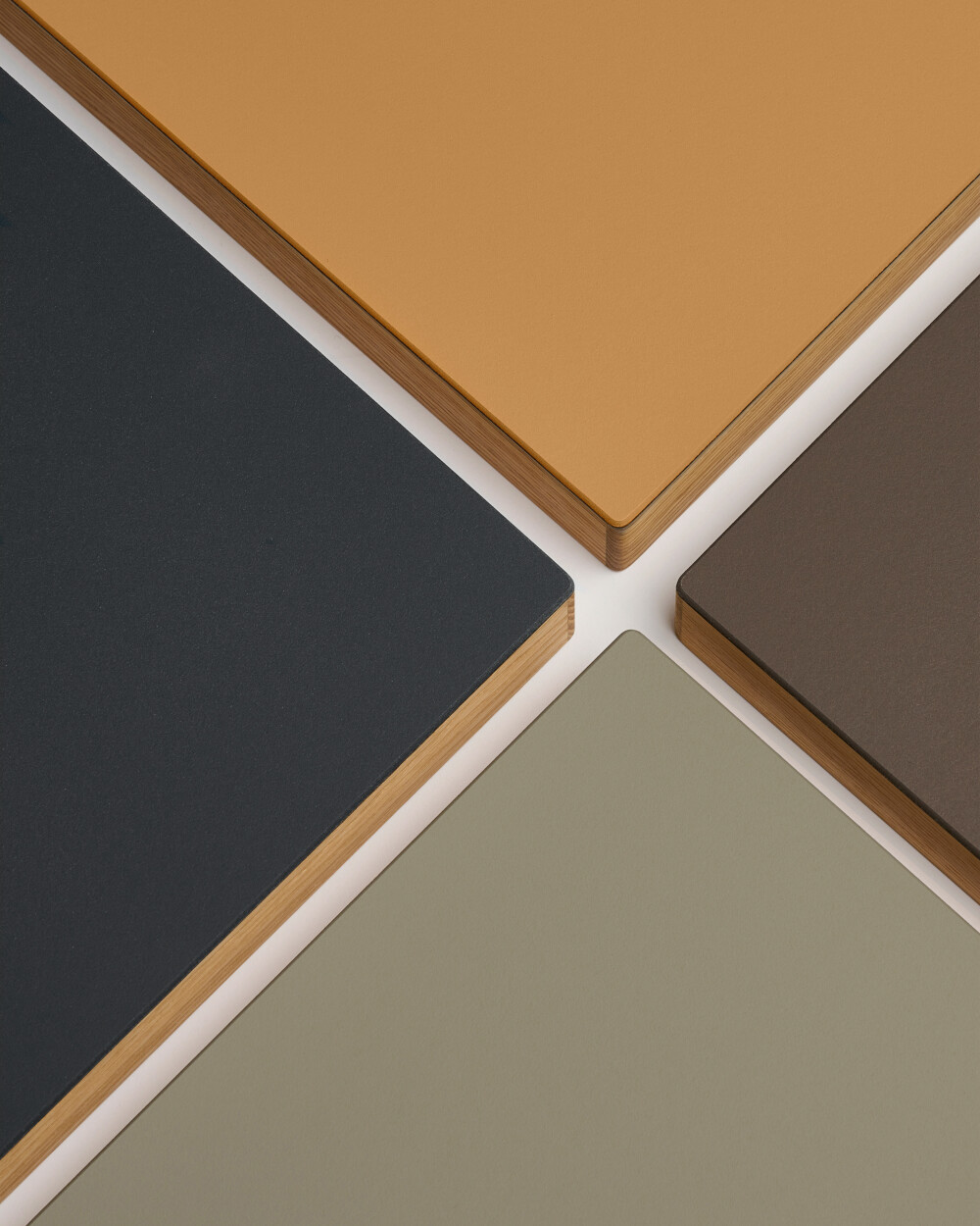 Four linoleum panels with oak edging in orange, mauve, pistachio green and anthracite – example of individual color configurations at Faust.